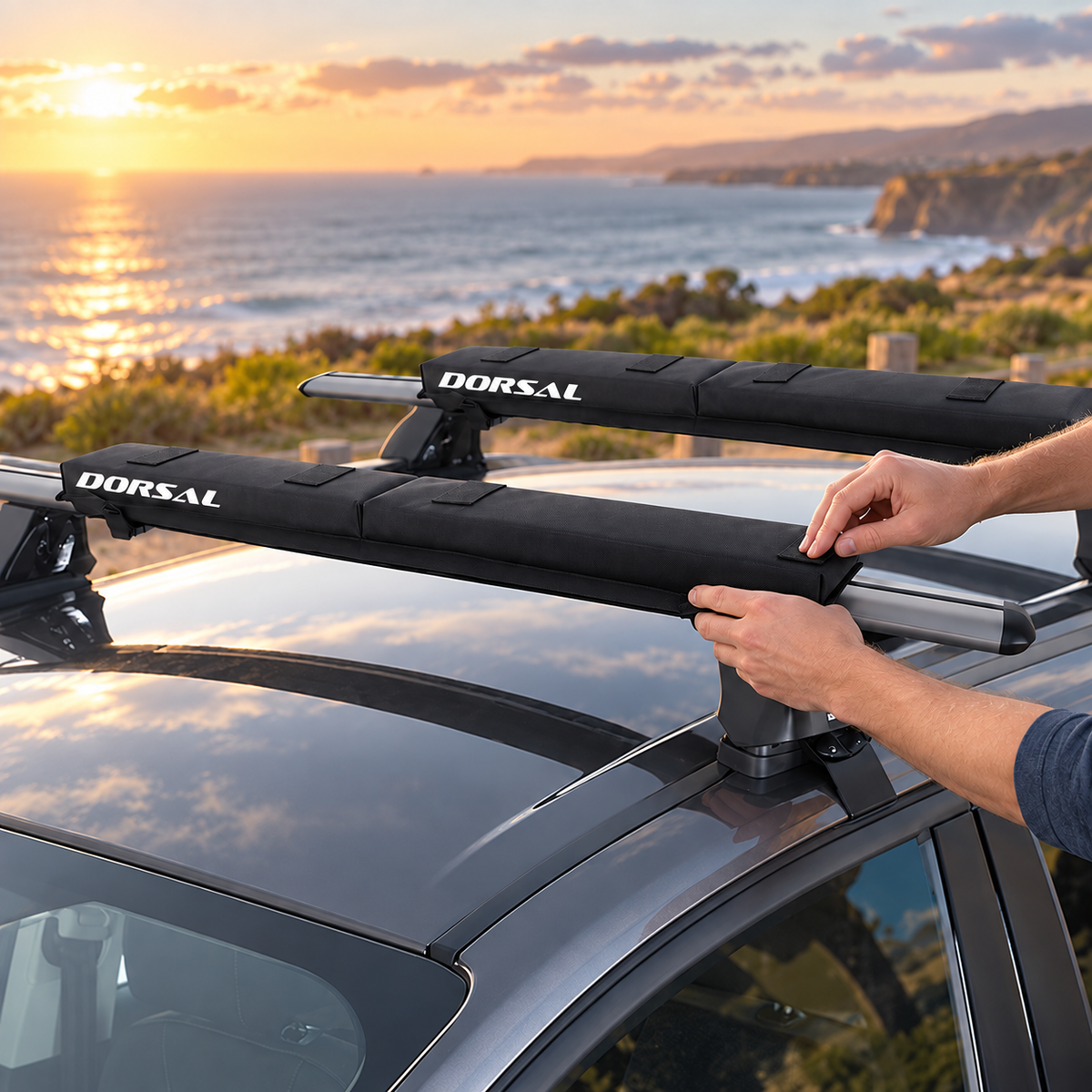 Illustrative installation view showing hands fitting a DORSAL folding pad onto a roof rack crossbar